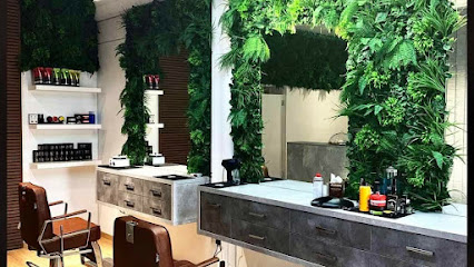 Interior of La Familia Barbershop, styling stations beneath a lush green plant wall in Kato Polemidia